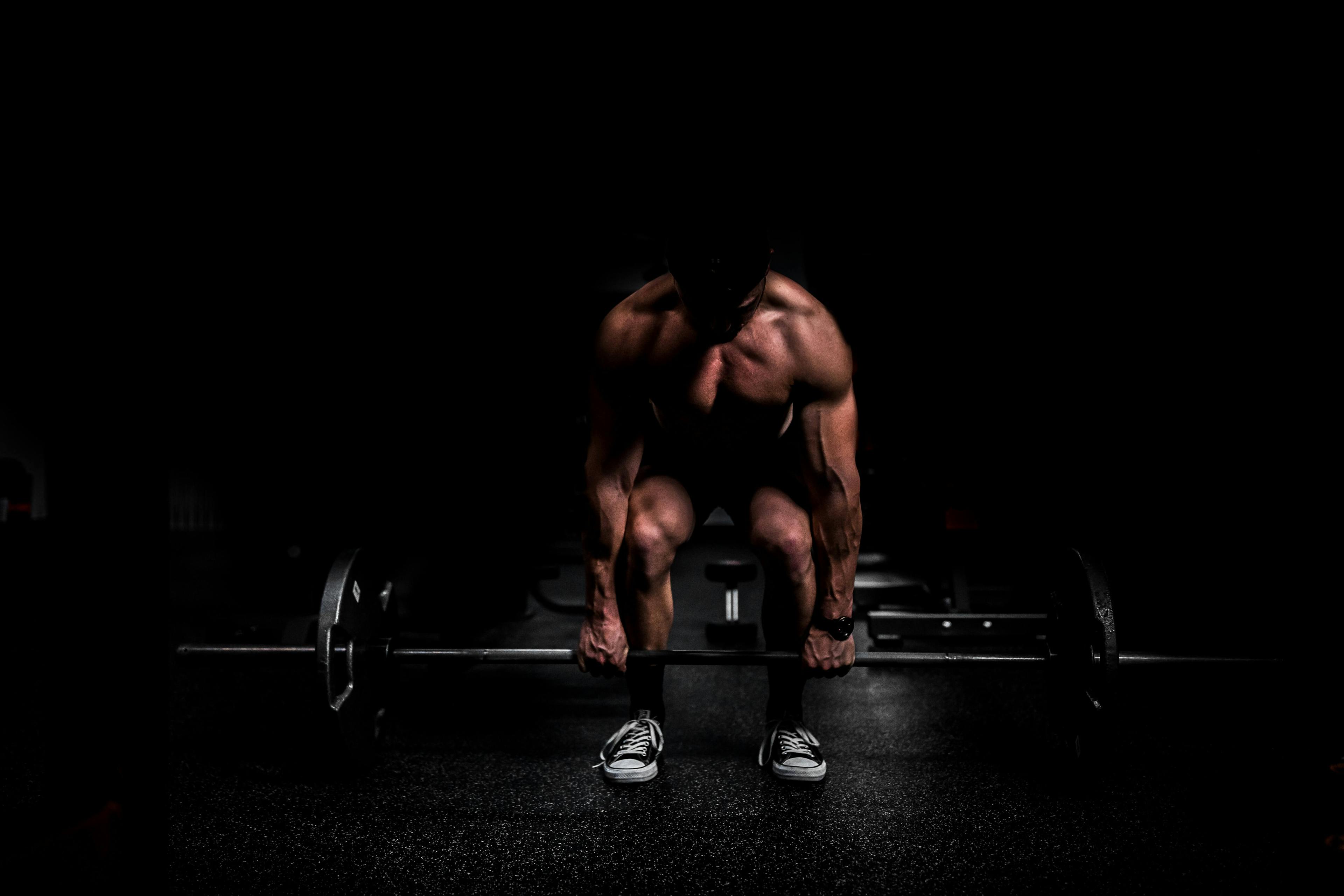 strong man lifting a bar in the dark